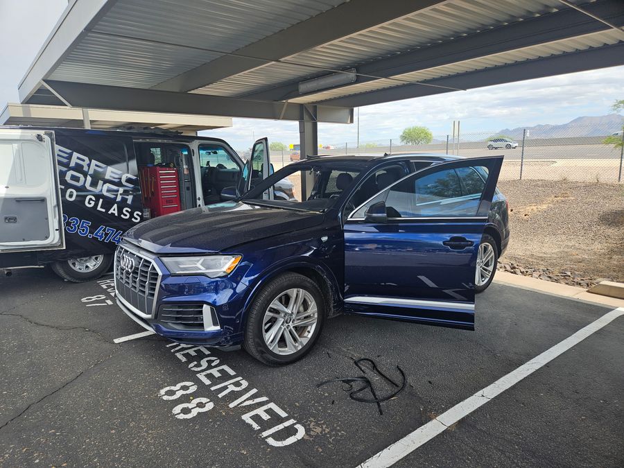 Audi Q7 with the windshield removed, mid-replacement under a carport
