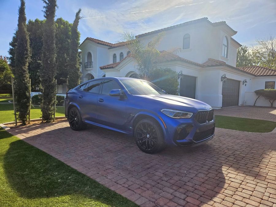 Matte blue BMW X6 M Competition parked in the driveway of a customer's home