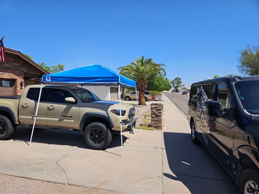 Shade canopy set up over a pickup truck in a customer's driveway for a windshield replacement